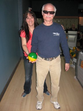 Monsieur Antonin Plante se prépare à lancer une boule de quille avec l'aide de madame Isabelle Mathieu.