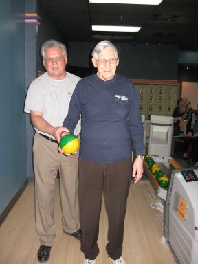 Monsieur Gilles Chevalier se prépare à lancer une boule de quille avec l'aide de monsieur André Chaput.