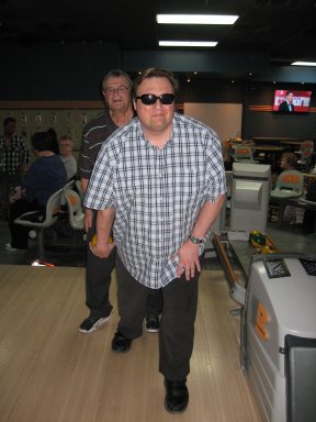 Monsieur Martin Morin se prépare à lancer une boule de quille avec l'aide de monsieur Louis-Philippe Ladouceur.