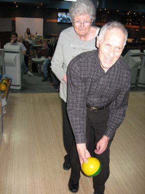 Monsieur Pierre Bissonnette se prépare à lancer une boule de quille avec l'aide de madame Solange Bissonnette.